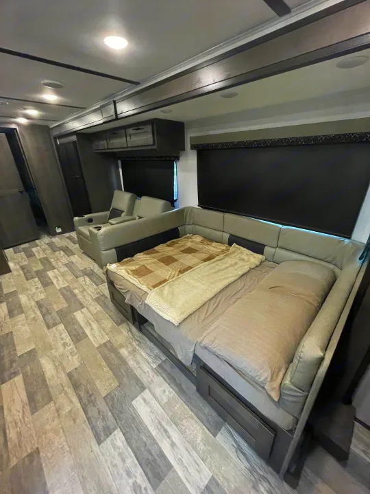 Modern RV rental interior: an L-shaped sofa converts to a bed, alongside recliners, on stylish grey flooring.. FR3 FR3 Motorhome 2023