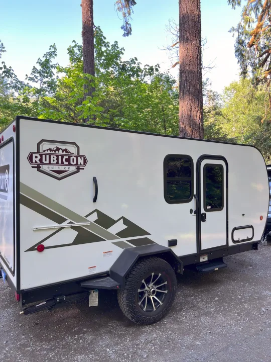 White Coleman Rubicon Edition RV rental at a scenic campsite. Ideal for outdoor adventures.. Dutchmen Coleman Rubicon 2023