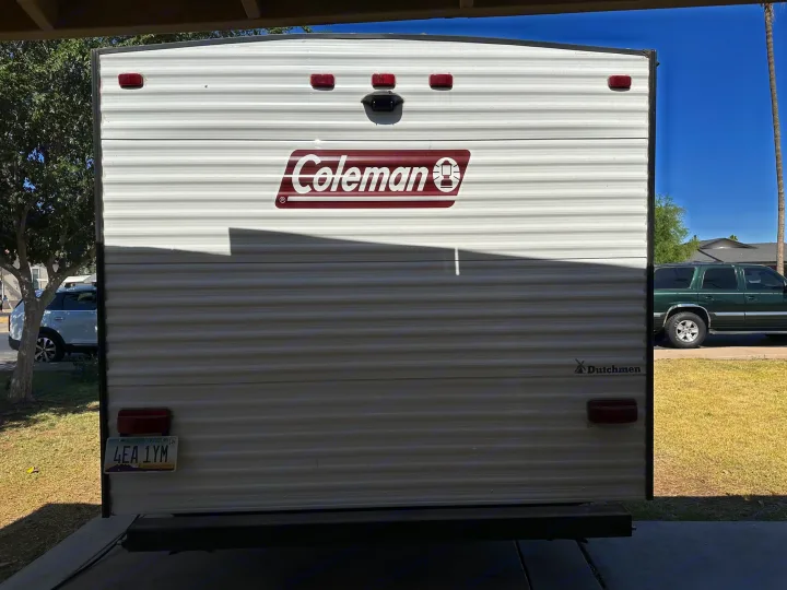 Rear of a white Coleman travel trailer, ideal for an RV rental. Visible are the Dutchmen logo and Arizona license plate.. Coleman Lantern LT 17B 2023