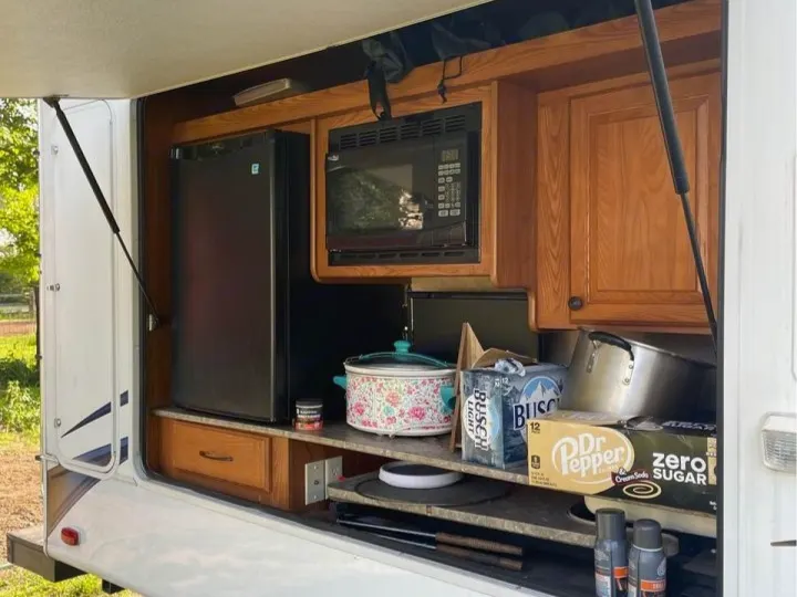 RV rental outdoor kitchen featuring a fridge, microwave, and cooking essentials for convenient camping adventures.. Heartland RVs Sundance 2012
