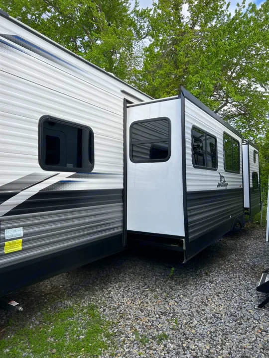 Side view of several modern travel trailers parked on a gravel lot. Ideal for an RV rental getaway.. Jayco Jay Flight 2022