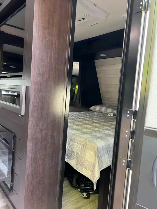 Inside this RV rental: an upper bunk with a cozy quilt, AC unit, and stored RV gear.. Jayco Jay Flight 2022