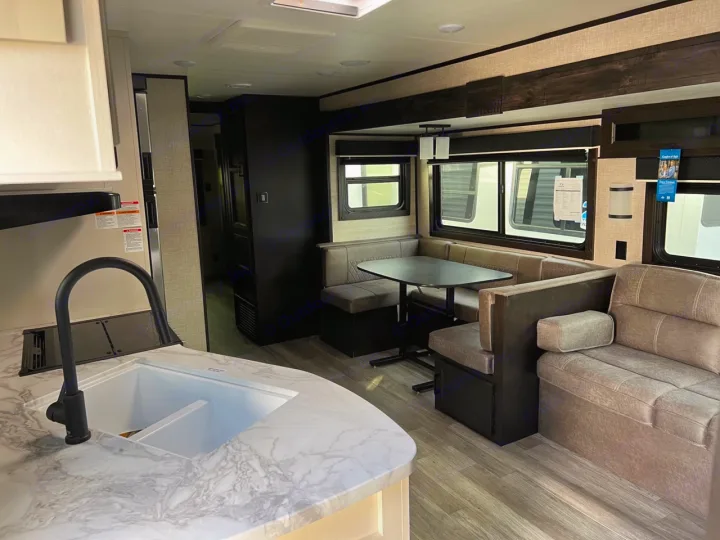Spacious RV rental interior with a well-equipped kitchen, dining booth, and comfy living area sofa.. Jayco Jay Flight 2022