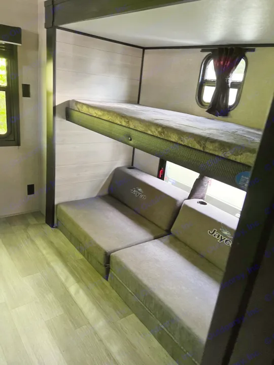 Interior of an RV rental, showing a bunk bed with window and a modular seating/bed area with Jayco branding.. Jayco Jay Flight 2022