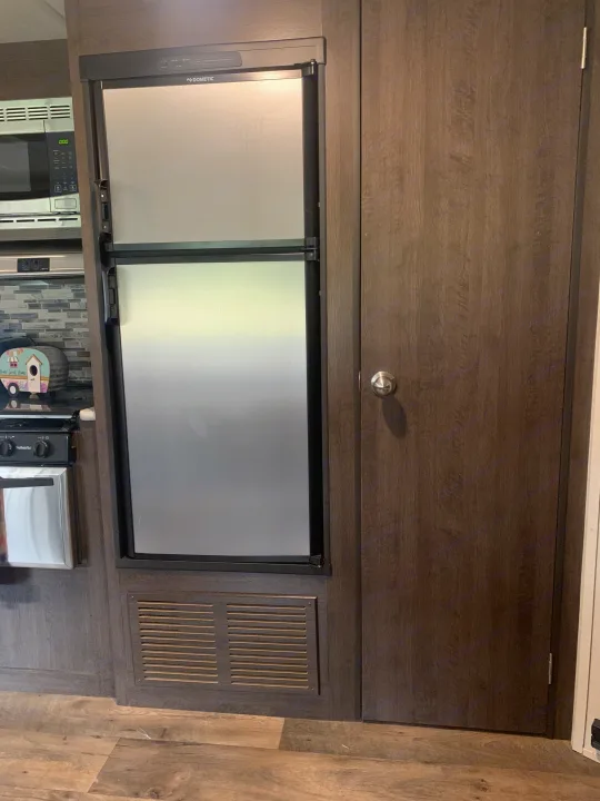 RV rental kitchen interior featuring a Dometic fridge, microwave, stovetop, and storage door.. Forest River Salem Cruise Lite 2018