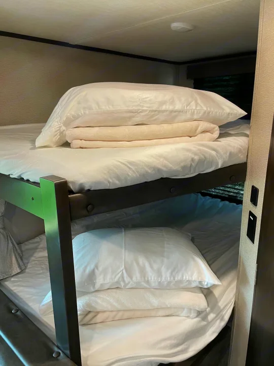 Clean bunk beds with white linens in an RV rental, offering comfortable sleeping space for travel adventures.. Grand Design Transcend 261BH 2022