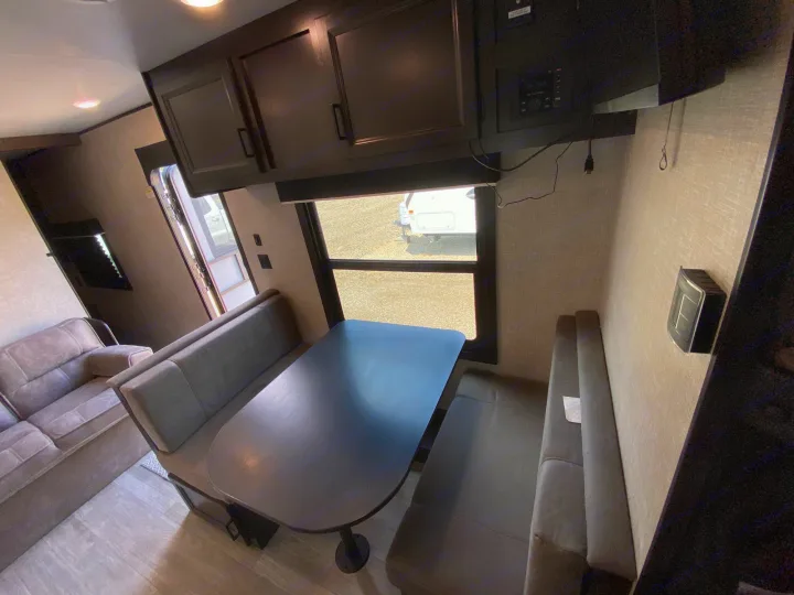 RV rental interior features a dinette with dark table & plush benches, and a separate sofa seating area.. Jayco Jay Flight SLX 2022
