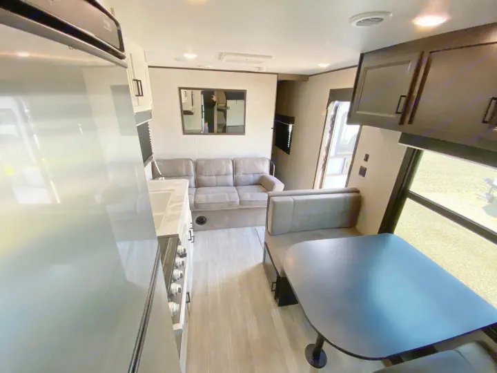Step inside this RV rental featuring a full kitchen with fridge, living area with sofa, and dining booth with table. Modern & comfy.. Jayco Jay Flight SLX 2022