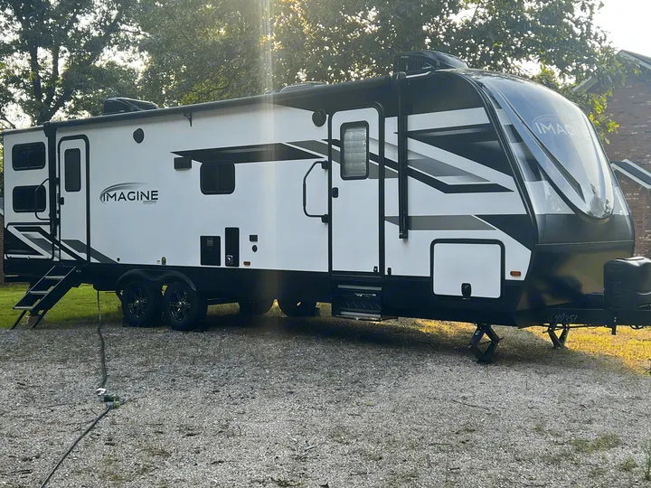White Grand Design Imagine travel trailer, ideal for your next RV rental adventure, parked on gravel.. Grand Design Imagine 2022