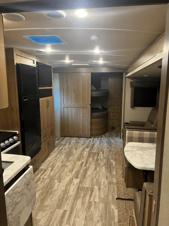 Spacious RV rental interior featuring a full kitchen, dining area, living space with recliners, and bunk beds.. Grand Design Imagine 2022
