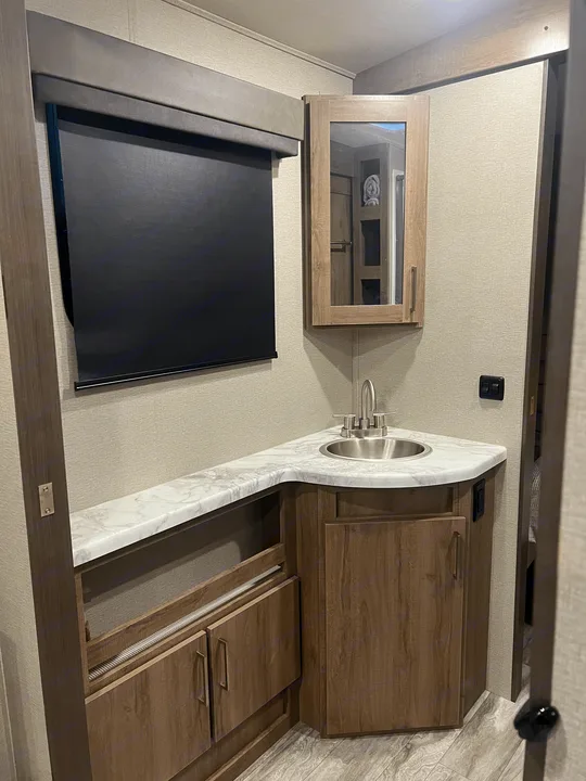 RV rental bathroom interior featuring a corner vanity, sink, mirrored cabinet, and storage.. Grand Design Imagine 2022