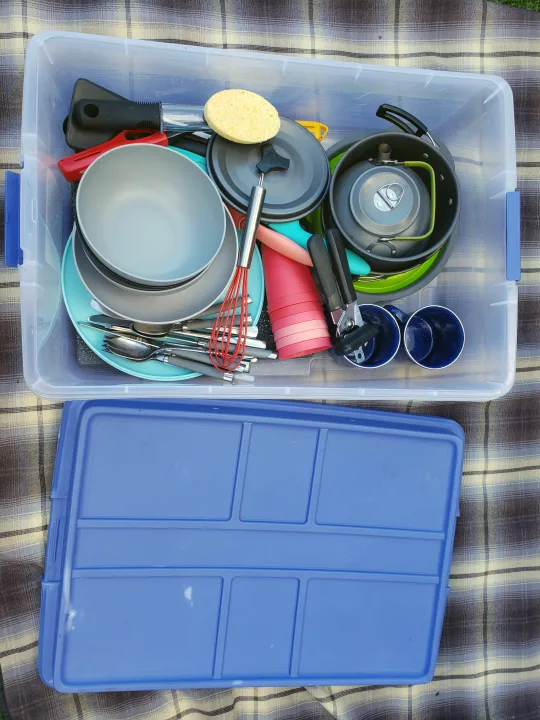 Organized RV rental kitchen gear: a clear tote full of camping pots, dishes, cutlery, and cups, ready for outdoor cooking.. Other Other 2015