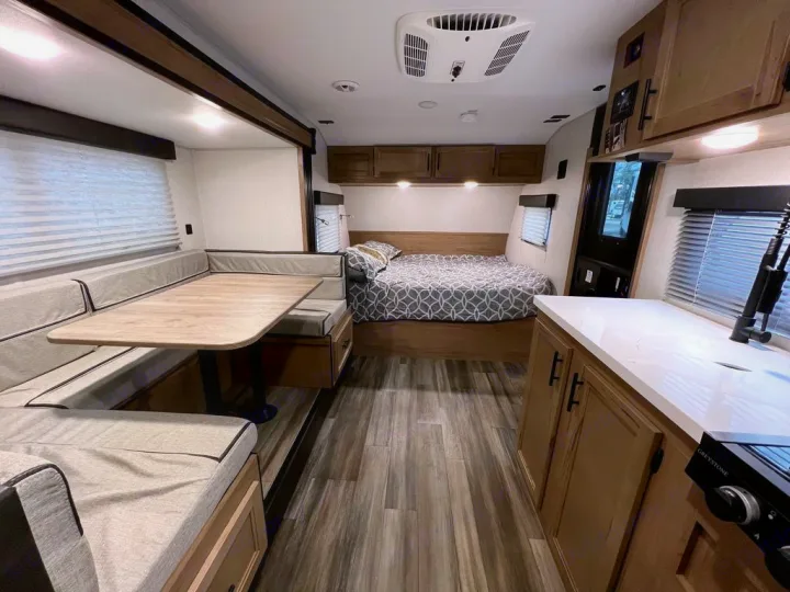 Spacious RV rental interior featuring a dinette, bed, & kitchen. Ideal for comfortable travel adventures.. Forest River Cherokee Wolf Pup 17JGBL 2023