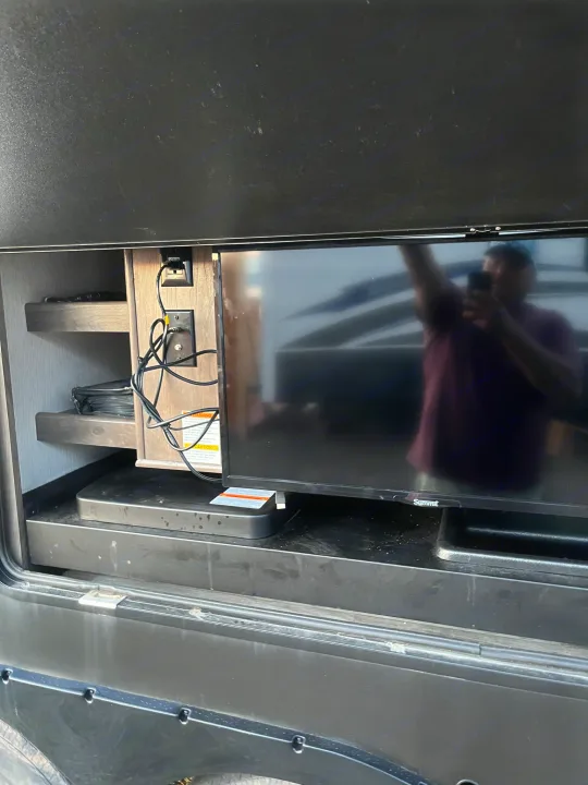 RV rental outdoor entertainment: TV, shelving with tangled cables in a bay. Ready for camping fun.. Heartland Torque 2020