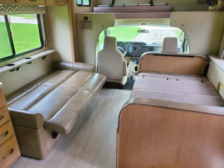 Inside an RV rental: a spacious interior featuring a convertible sofa, bed area, and front cockpit.. Thor Motor Coach Daybreak 30D 2020