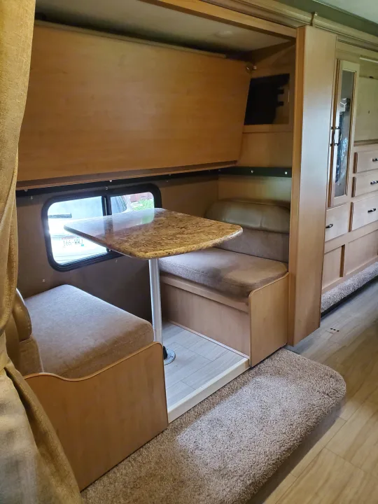 RV rental interior: A cozy dinette with window, benches, table, and overhead storage for comfortable travel.. Thor Motor Coach Daybreak 30D 2020