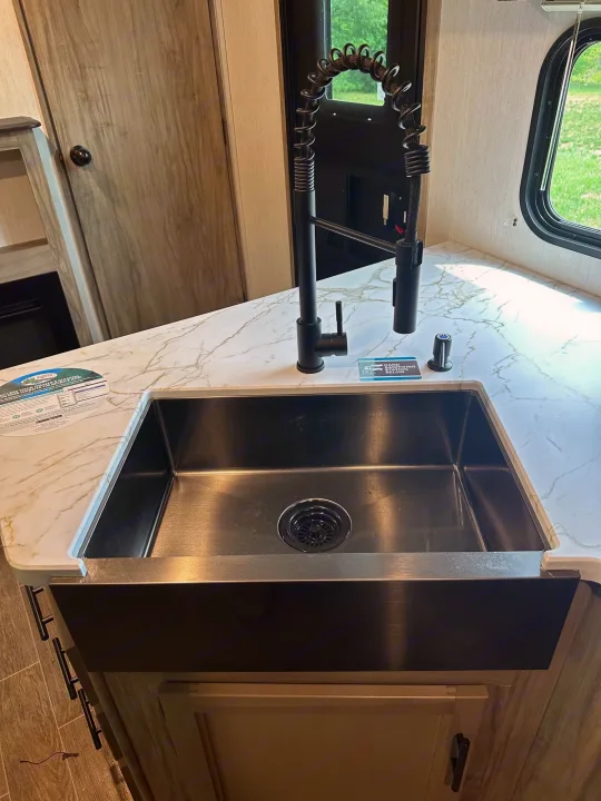 RV rental interior: Modern kitchen with deep black sink, spring-coil faucet, and veined countertops.. Forest River Cherokee Alpha Wolf 2022