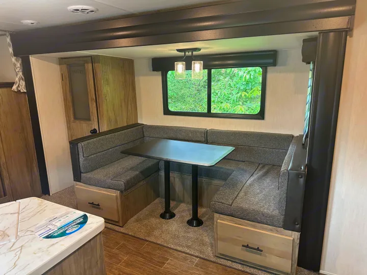 RV rental interior: Cozy dinette setup with U-shaped bench seating, central table, under-seat storage, and large window.. Forest River Cherokee Alpha Wolf 2022