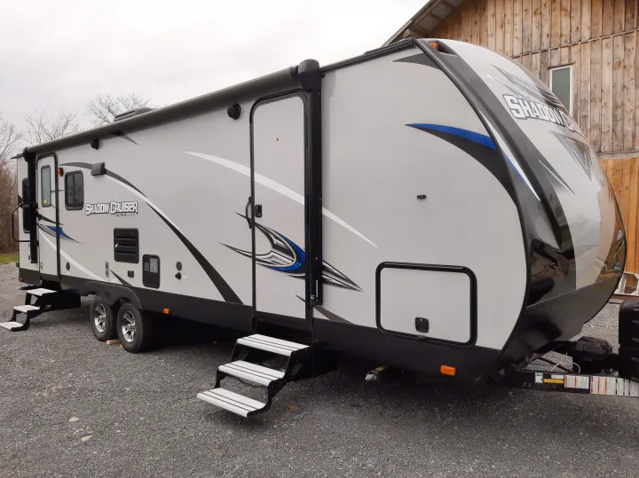 Light gray Shadow Cruiser travel trailer rv rental, detailed with black/blue graphics, parked on gravel with steps down.. Cruiser RV Shadow Cruiser 2019