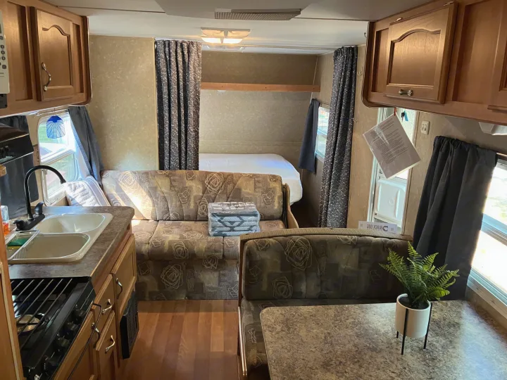 Bright rv rental interior: kitchen with sink & stove, cozy sofa, dinette, & bed. Your next road trip awaits!. Gulf Stream Ameri-Lite 25 BS 2008