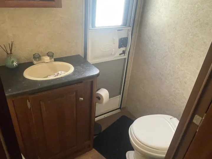 An RV rental bathroom showing a compact vanity with sink, toilet, and main door. Essential amenities in a small space.. Keystone Bullet Premier 2014