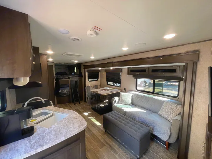 Spacious RV rental interior featuring a kitchen, living area with a sofa, dining table, and cozy bunk beds.. Jayco Jay Flight SLX 2021