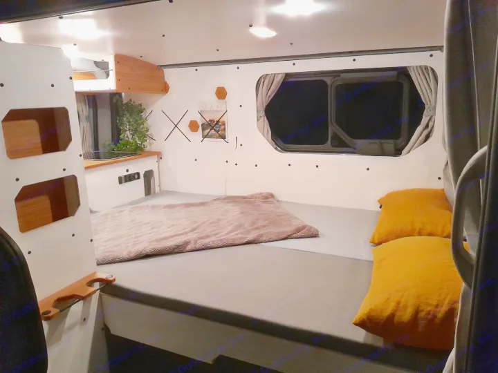 This RV rental's cozy interior features a bed, smart storage, and a compact kitchen, providing a complete mobile home.. Renault Traifc + aménagement NW Van Mania 2019