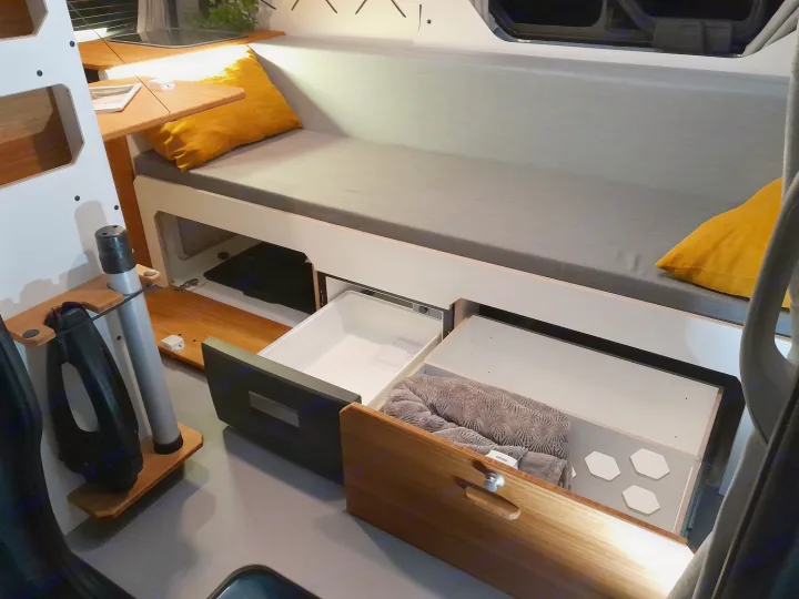 RV rental's compact living space features a comfy bed, integrated fridge, and smart storage solutions.. Renault Traifc + aménagement NW Van Mania 2019
