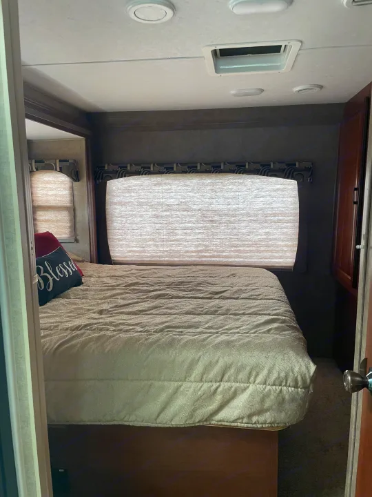 Cozy RV rental bedroom with a comfortable bed, window blinds, and integrated ceiling lighting/AC vents.. Forest River Sunseeker 2016