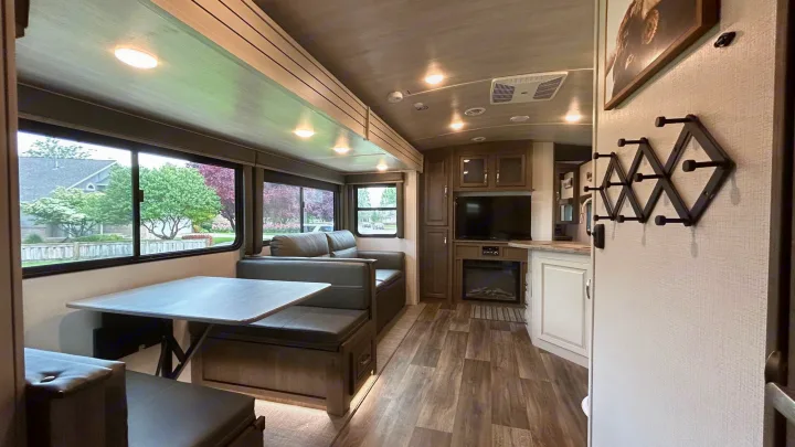 Modern RV rental interior with a dining area, sofa, TV, electric fireplace, and kitchen island. Perfect for travel!. Keystone Cougar Half-ton 2022