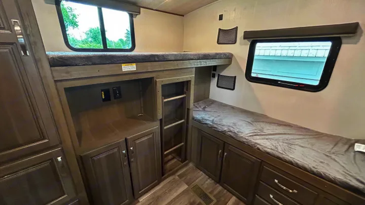 Inside an RV rental: view of bunk beds, storage cabinets, and a ladder for upper access.. Keystone Cougar Half-ton 2022