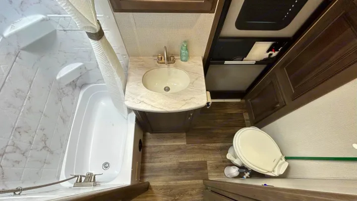 Bright, compact RV bathroom with a shower/tub, sink vanity, and toilet. Ready for your rv rental adventure.. Keystone Cougar Half-ton 2022