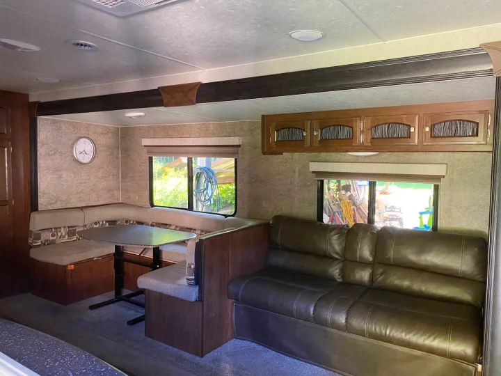 An inviting RV rental living space featuring a dinette, comfy couch, and overhead storage. Great for family road trips.. Coachmen Freedom Express 2020