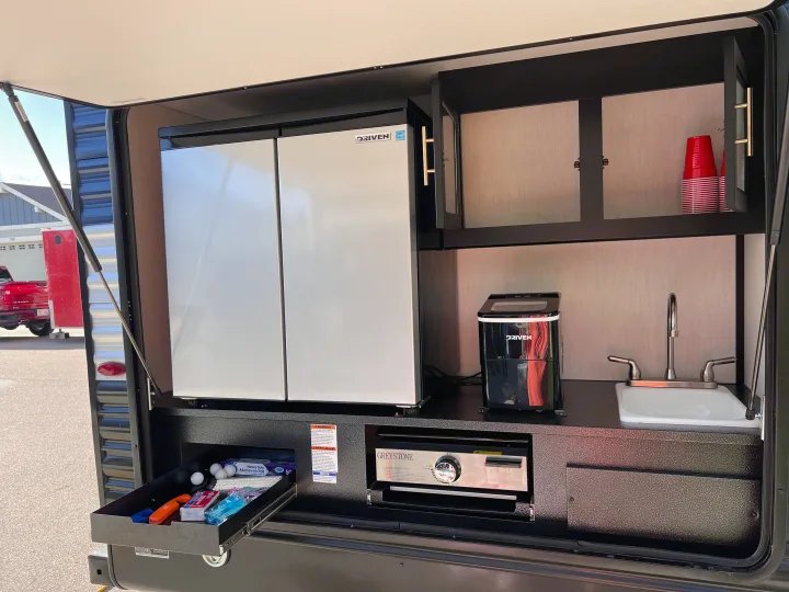 This RV rental outdoor kitchen features a large fridge, ice maker, sink, and a Greystone cooktop for easy meal prep.. Forest River Cherokee 2022