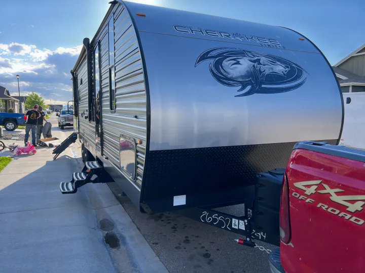 Preparing for an RV rental adventure! A silver Cherokee travel trailer is hooked to a red pickup truck on a sunny day.. Forest River Cherokee 2022