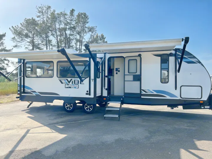 This white Forest River Vibe travel trailer RV rental, with its awning extended and door open, is ready for your adventure.. Forest River Vibe 2022