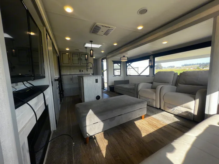 Spacious rv rental: Bright interior featuring a full kitchen island, comfortable recliners, & living area with large windows.. Forest River Vibe 2022