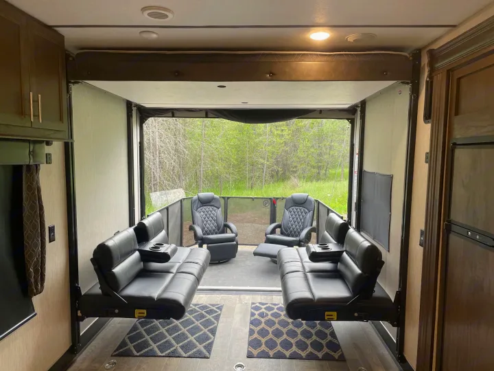 Experience this rv rental's versatile toy hauler living space with comfy suspended sofas, recliners, and a serene nature view.. Forest River Cherokee Wolf Pack 2020