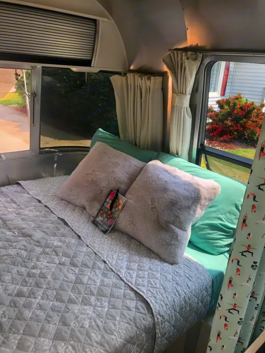 Cozy Airstream RV rental bedroom: plush pillows, quilted bed, light teal sheets, and windows with scenic views.. Airstream Sport 2019