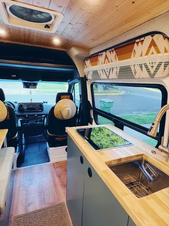 Step into a modern RV rental, featuring a wood-paneled ceiling, a functional kitchen with stove and sink, and seating.. Freightliner Sprinter 2500 2019