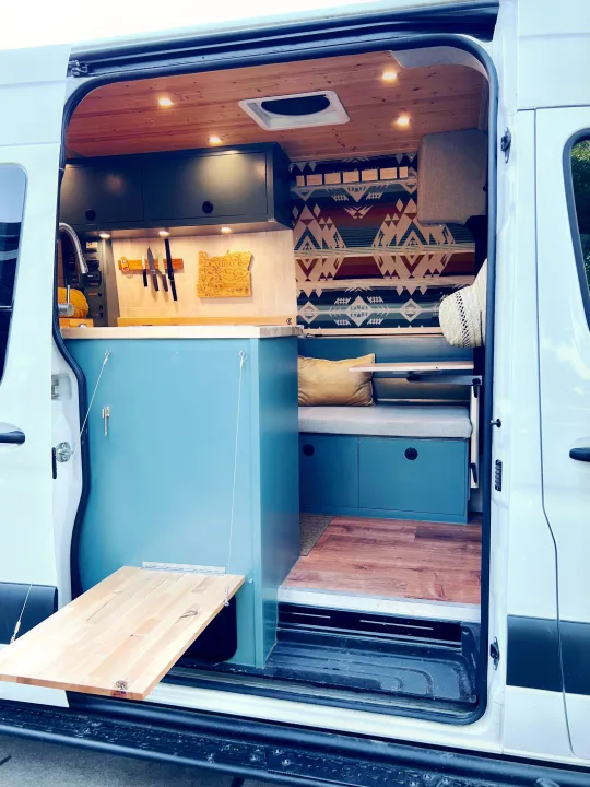 Inside a modern RV rental, find a compact kitchen, cozy seating area with storage, and a handy fold-out table. Ideal for adventures.. Freightliner Sprinter 2500 2019