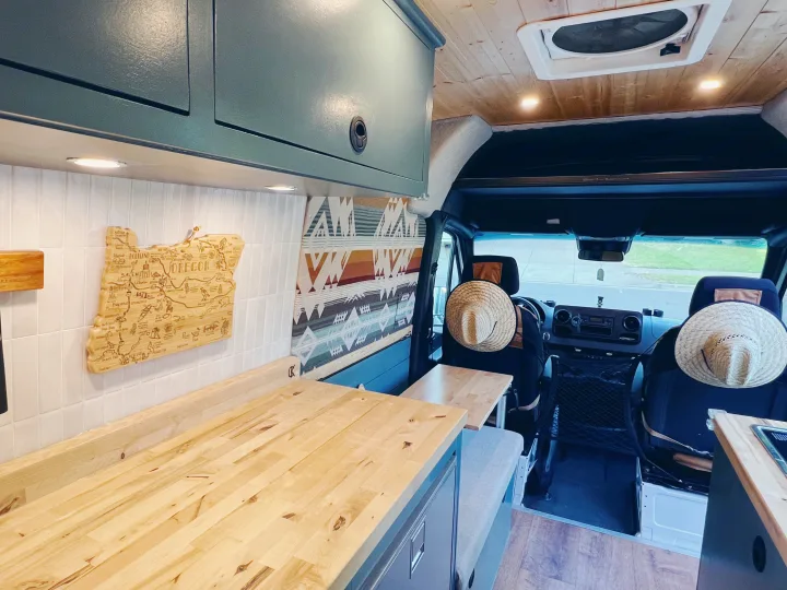 RV rental's inviting interior: light wood kitchen counters, teal cabinets, and an Oregon map define this cozy mobile space.. Freightliner Sprinter 2500 2019
