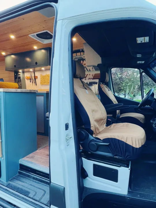 This customized camper van interior, ideal for an rv rental, features a compact kitchen and comfortable front seating.. Freightliner Sprinter 2500 2019