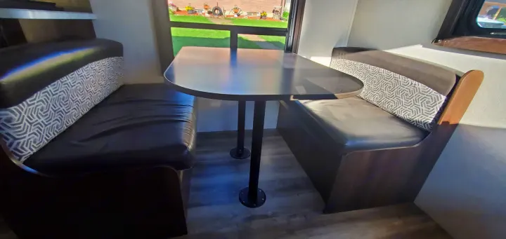 Cozy RV rental dinette with comfortable dark seating, patterned backrests, and a compact table for meals.. Jayco Flight 2020
