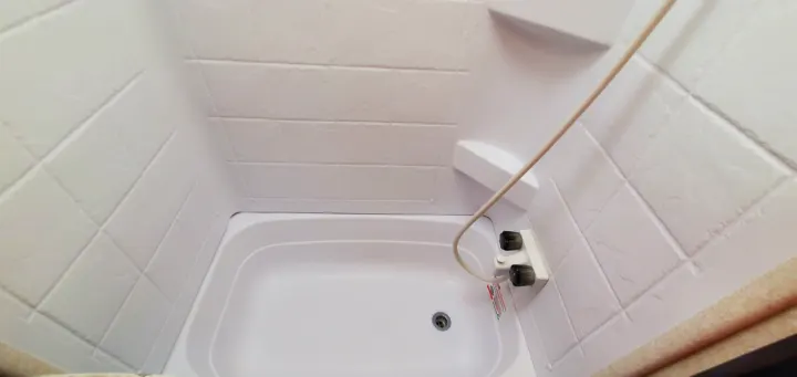 Compact RV rental shower-tub unit with white faux tile walls and integrated shelf, ideal for small spaces.. Jayco Flight 2020