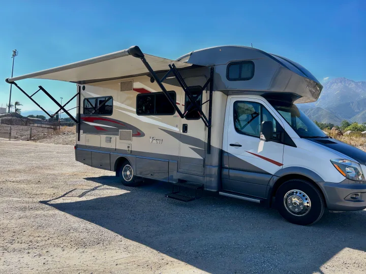 Discover this stylish Winnebago View Class C RV, available for rv rental! Awning extended on a sunny day with mountains.. Winnebago View 2017