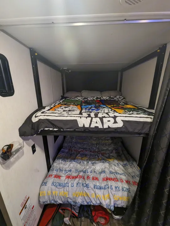 Cozy bunk beds in an RV rental, with Star Wars and Hogwarts bedding, ready for family travel and adventure.. Forest River Cherokee Wolf Pack Toy Hauler 2022