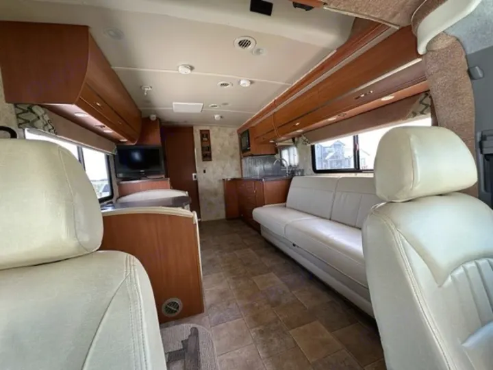 Spacious RV rental interior with light furnishings, showing living area, kitchen, and ample seating. Perfect for travel.. Winnebago View 2011