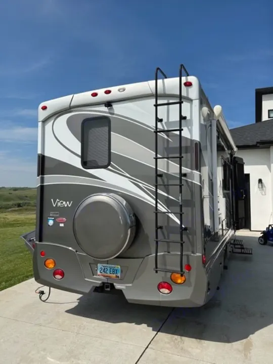 This back view of a gray and white RV, complete with ladder and spare tire, is perfect for your next rv rental.. Winnebago View 2011
