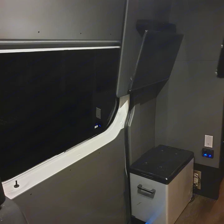 RV rental van conversion: Dark gray interior with large window, portable fridge, power outlets, and open overhead storage.. Mercedes Sprinter Freight Liner 2020